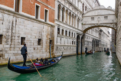 People in canal against buildings