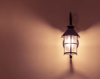 Close-up of illuminated lamp against wall