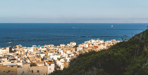 High angle view of townscape by sea against sky