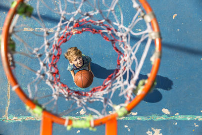 Boy standing with basketball under hoop at sports court