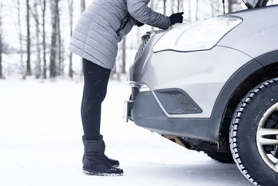 Man standing by car on snow covered road during winter