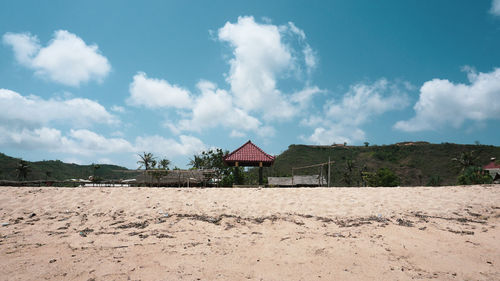 House on field by buildings against sky
