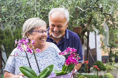 Smiling senior couple holding plants at back yard