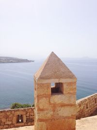 Built structure by sea against clear sky