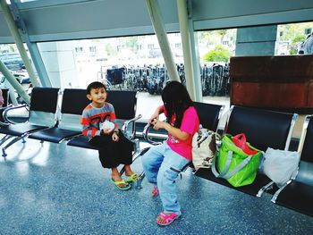 Siblings sitting on seat at airport