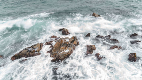 High angle view of waves breaking on rocks