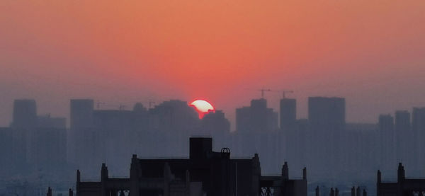 Silhouette buildings against sky during sunset