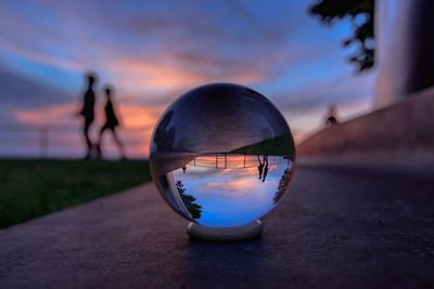 Upside down image of silhouette ball on glass against sunset sky