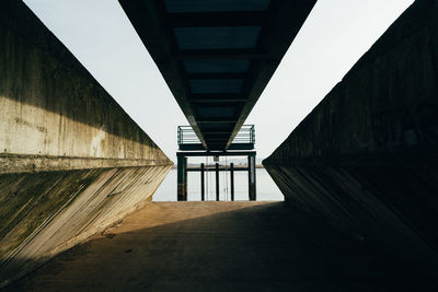 Low angle view of bridge amidst buildings against sky