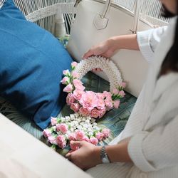 Midsection of woman holding flower decoration on sofa at home