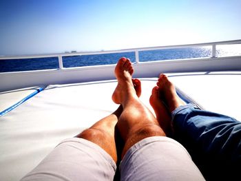 Low section of man relaxing on boat sailing in sea