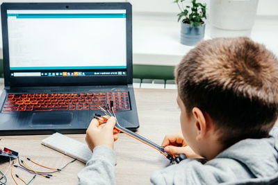 A boy plugging cables to sensor chips while learning arduino coding and robotics