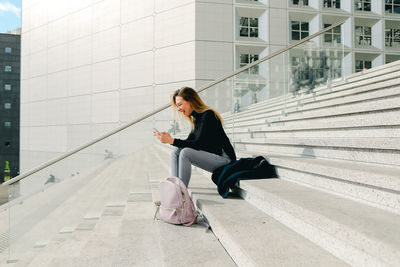 Full length of young woman walking on footpath in city