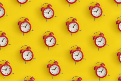 Pattern composition of black antique alarm clock on yellow background. flat lay composition.