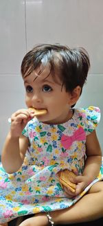 Close-up of cute girl eating snacks while sitting at home