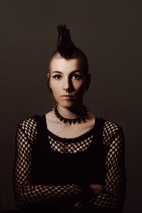 Portrait of young woman against black background