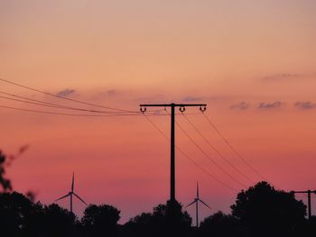 Low angle view of silhouette electricity pylon against romantic sky