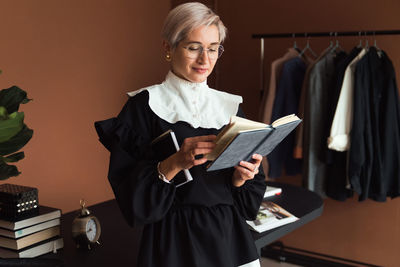 Fashion woman in vintage black and white dress holding planner, standing in modern office