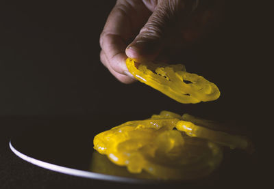 Close-up of hand holding leaf against black background