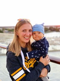 Portrait of happy mother and daughter by water against clear sky