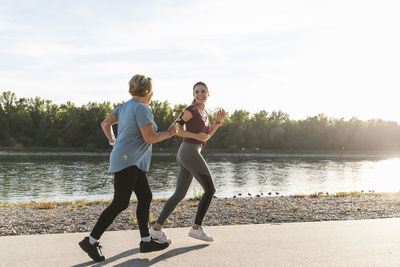 Granddaughter and grandmother having fun, jogging together at the river