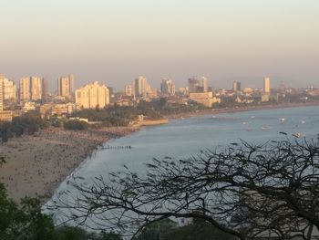 Sea by cityscape against sky