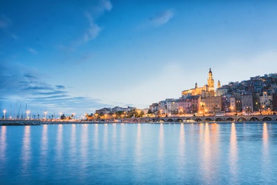 City at waterfront against blue sky