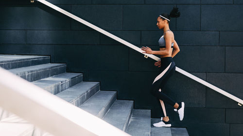 Full length of woman climbing steps against wall