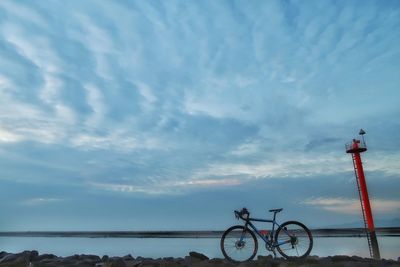 Bicycle by sea against sky