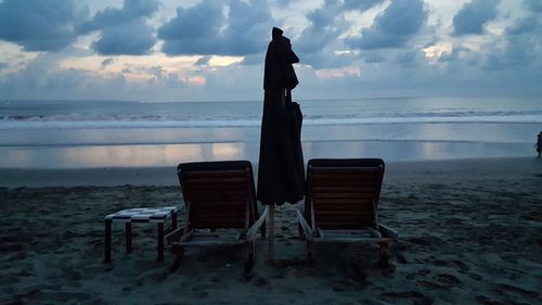 Deck chairs on beach against sky