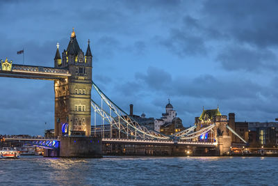 View of illuminated bridge over river against sky in city