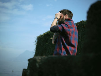 Full length of a man holding drink against sky