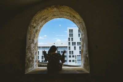 Rear view of woman looking through window in building