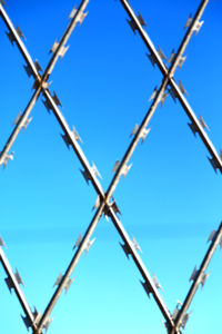 Low angle view of chainlink fence against blue sky