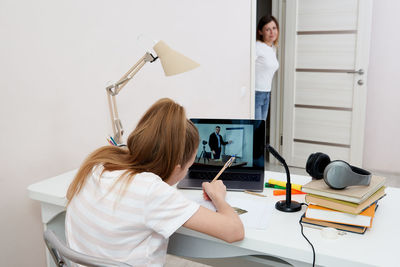 Mother checking on daughter attending online class