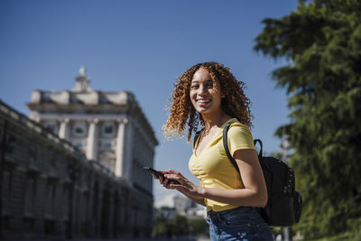 Young woman using mobile phone against sky