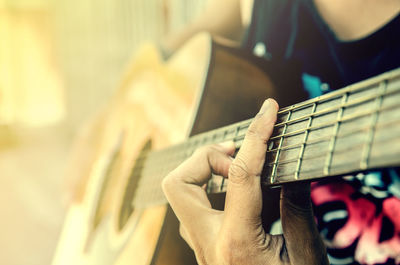 Midsection of man playing guitar