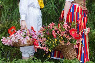 Midsection of woman holding flowering plants in basket