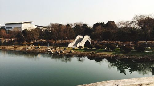 Footbridge by lake against sky in park