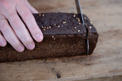 Sliced rye bread stock photo. the man cuts whole-wheat rye bread on a wooden cutting board.