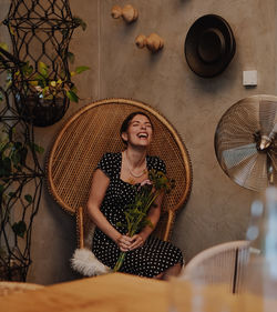 Woman laughing while sitting with flowers on chair