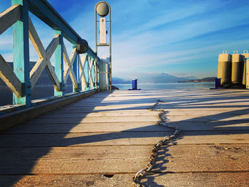 Footpath by bridge against blue sky