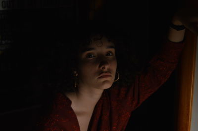 Close-up portrait of young woman in darkroom