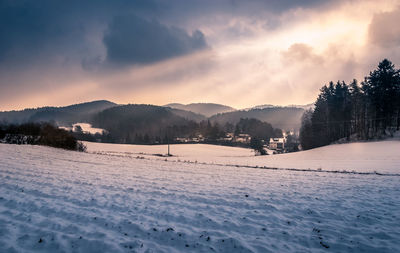 Scenic view of snow covered field against sky at sunset