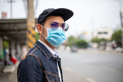 Man wearing mask while standing on road in city