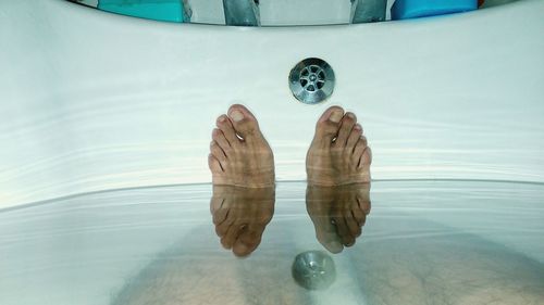 Low section of man with reflection in bathtub