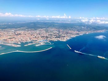 Aerial view of city by sea against blue sky