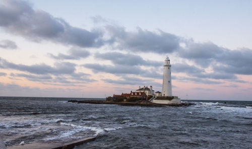 Lighthouse by sea against sky