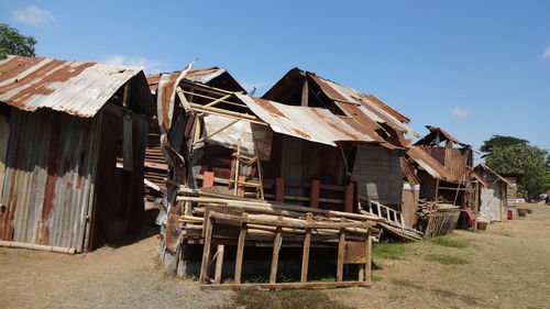 Old wooden house by building against clear sky