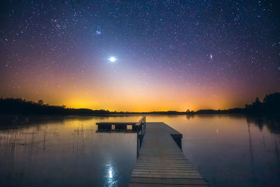 Pier over lake against sky at night